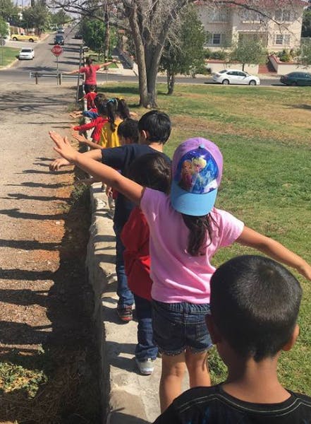 Children standing in a line with arms outstretched