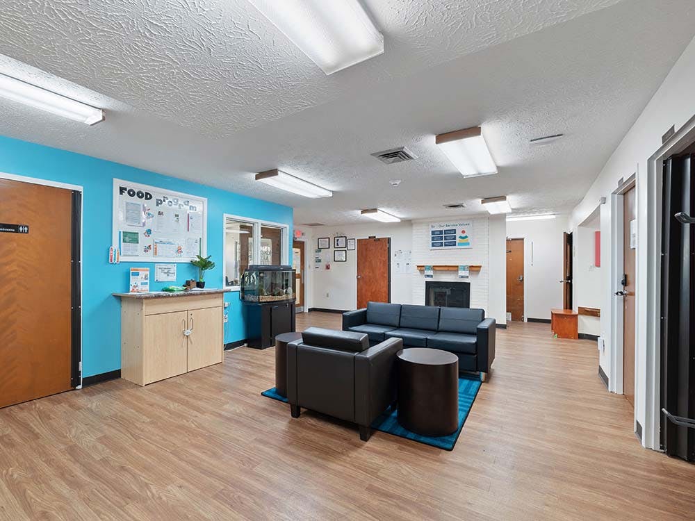 Waiting area with sofas, a bulletin board with text, and a fish tank