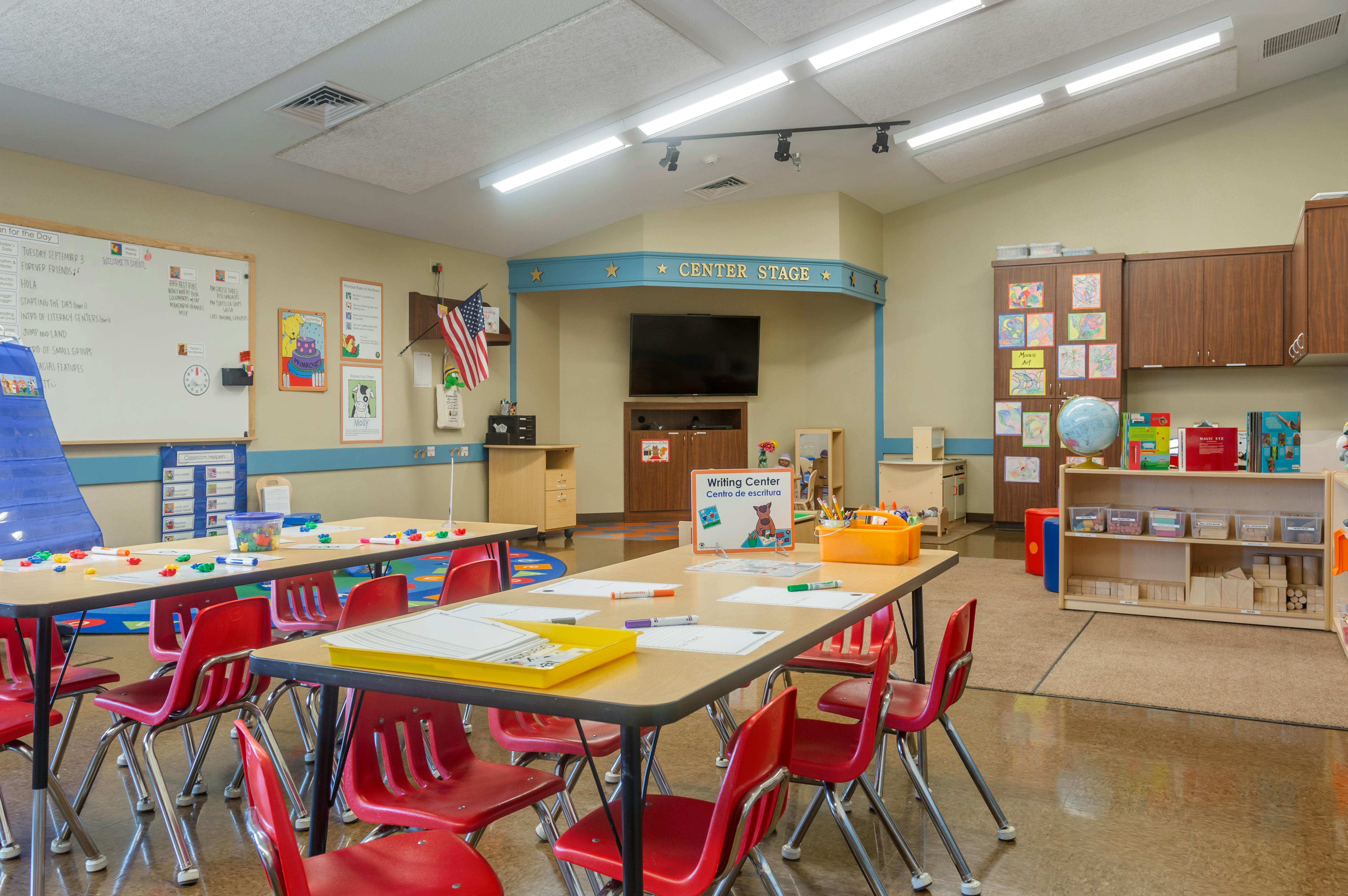 Classroom with tables, red chairs, and a whiteboard