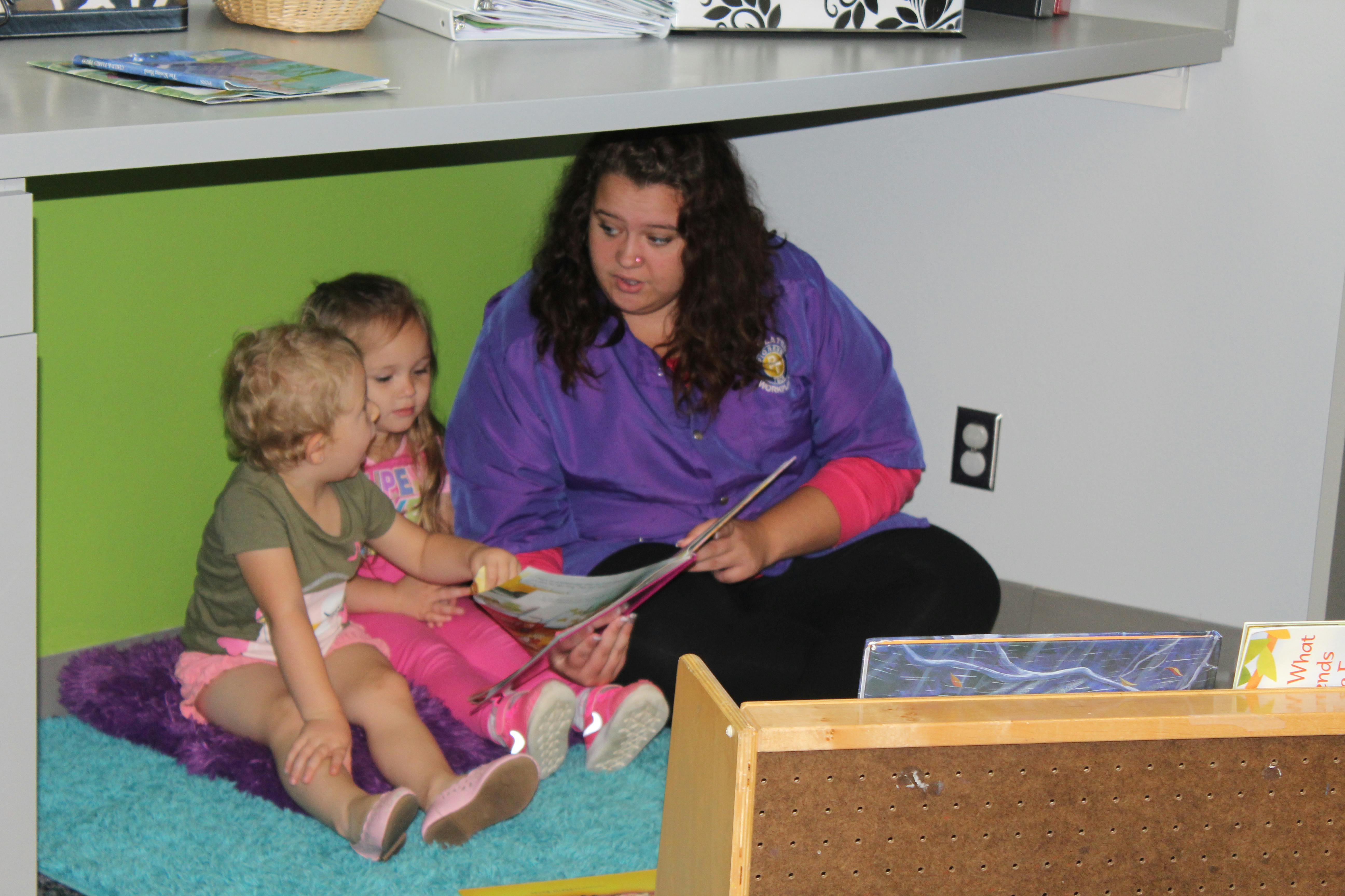 Person reading a book to two children