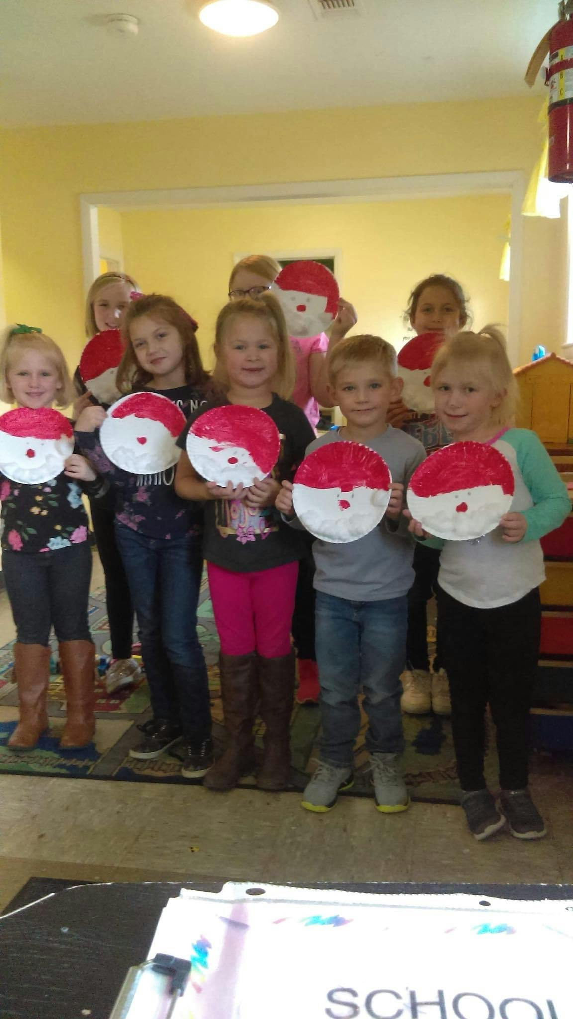Group of children holding paper plate crafts with red and white painted design