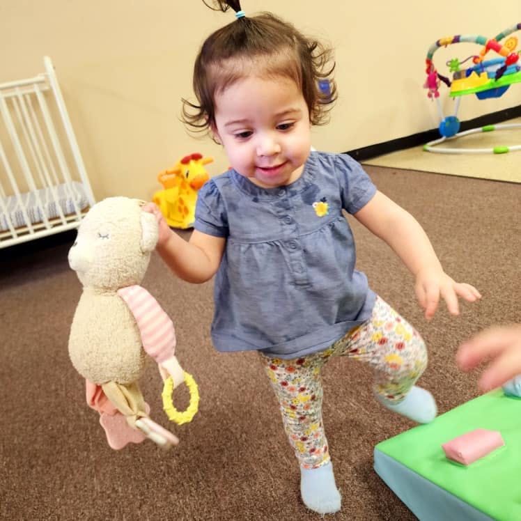 Child holding a stuffed animal while standing