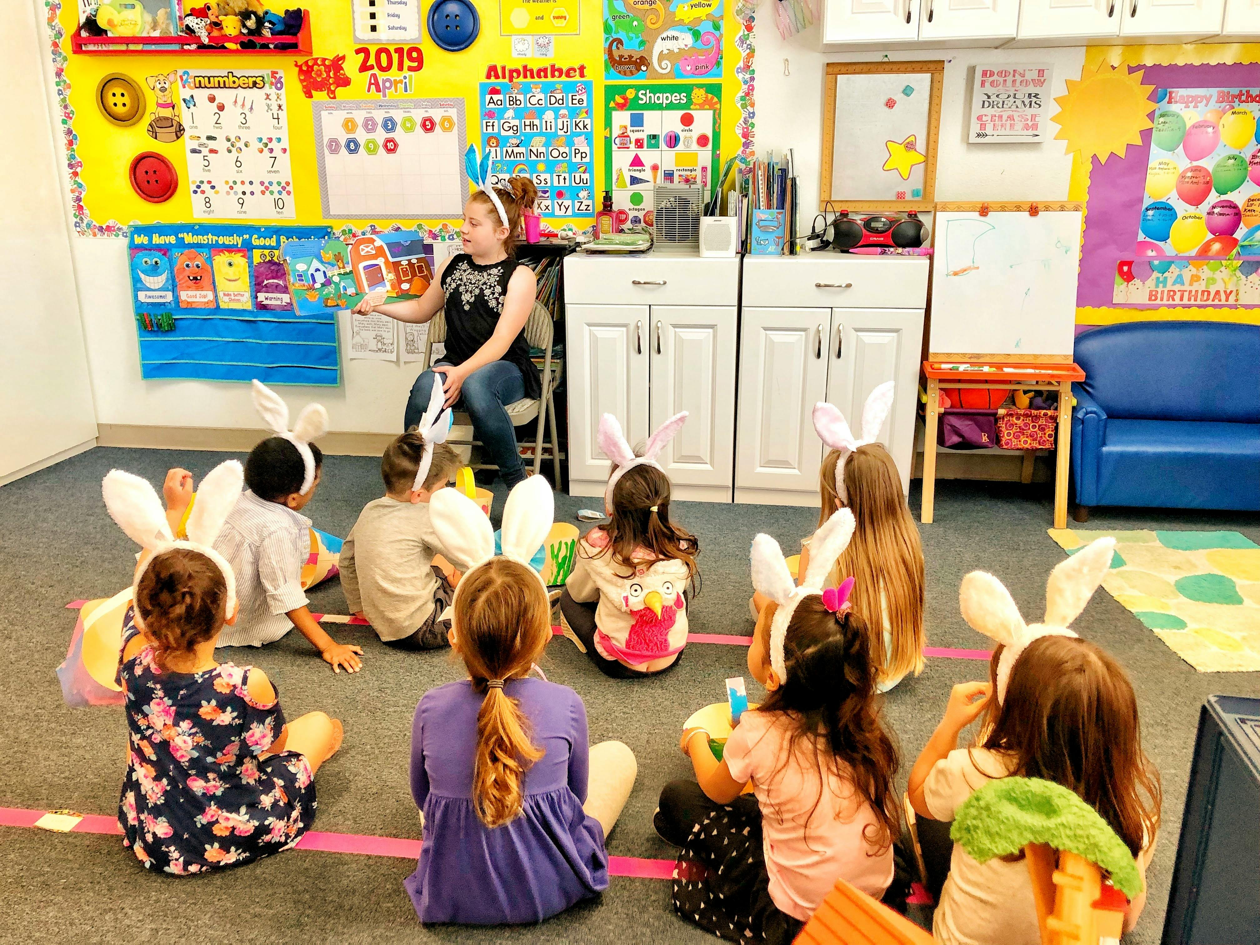 Person reading to children wearing bunny ears in a classroom