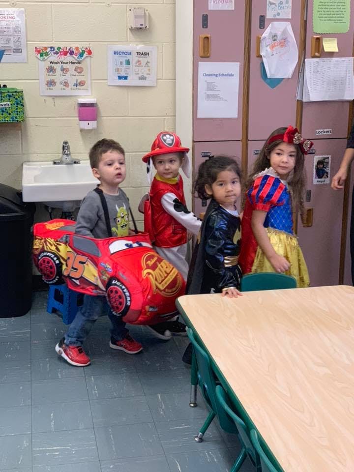 Four children in costumes standing in a classroom