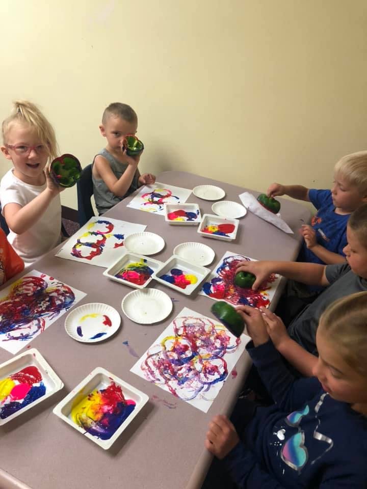 Children painting with vegetables at a table