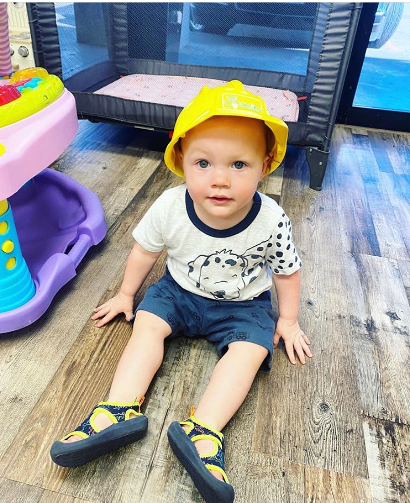 Child in a yellow hat sitting on a wooden floor