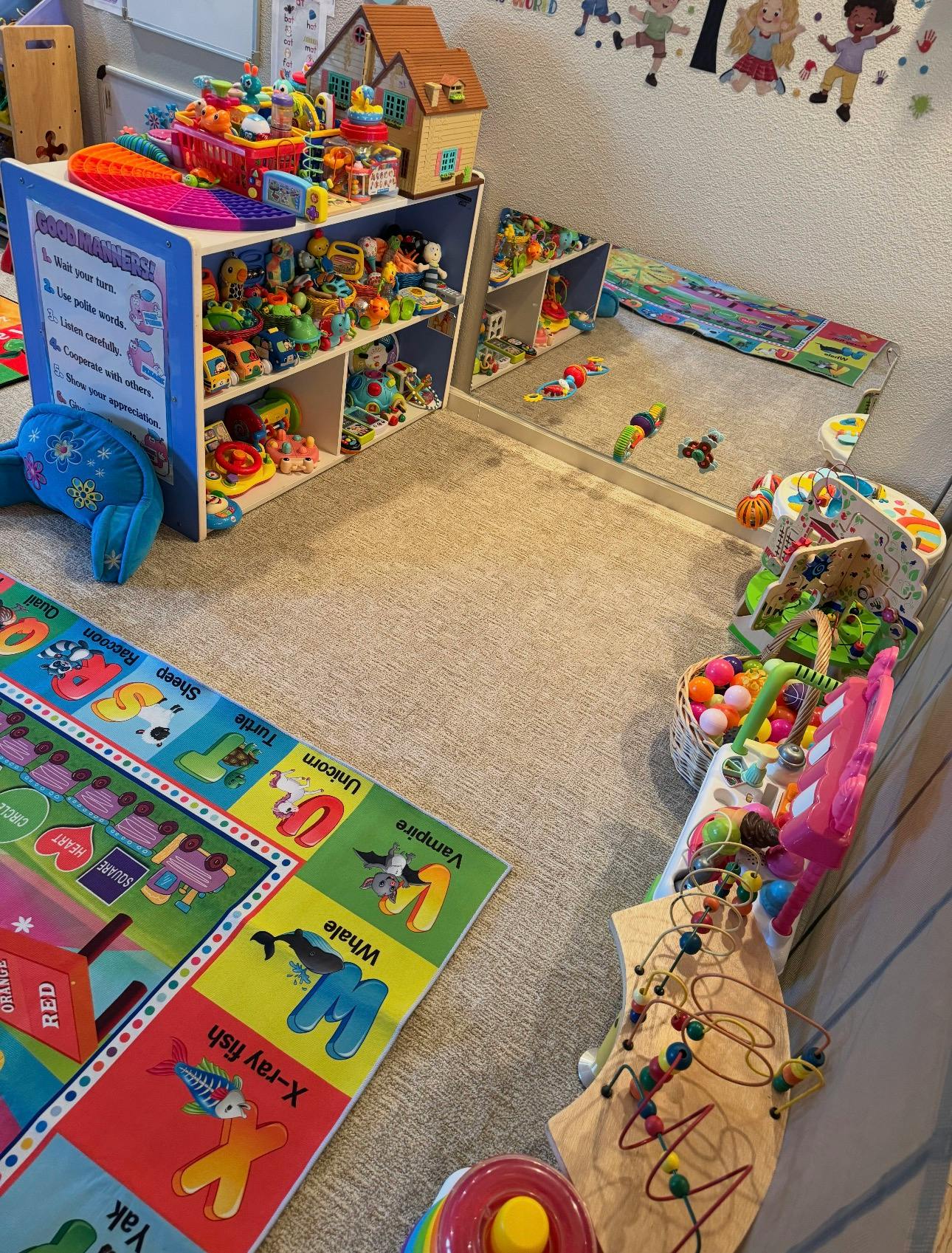 Playroom with alphabet rug and shelves filled with assorted toys