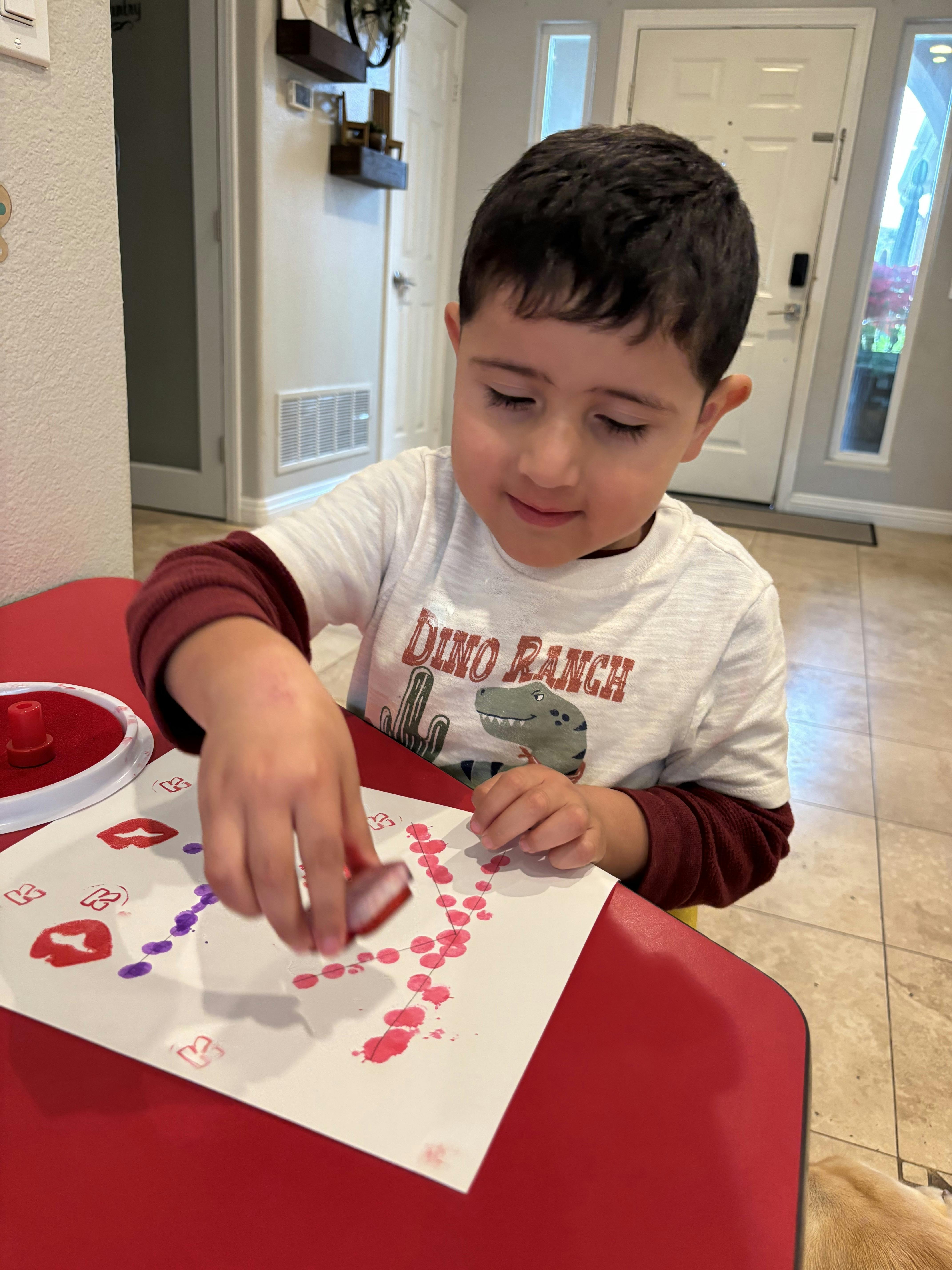 Child stamping on paper with red and purple ink