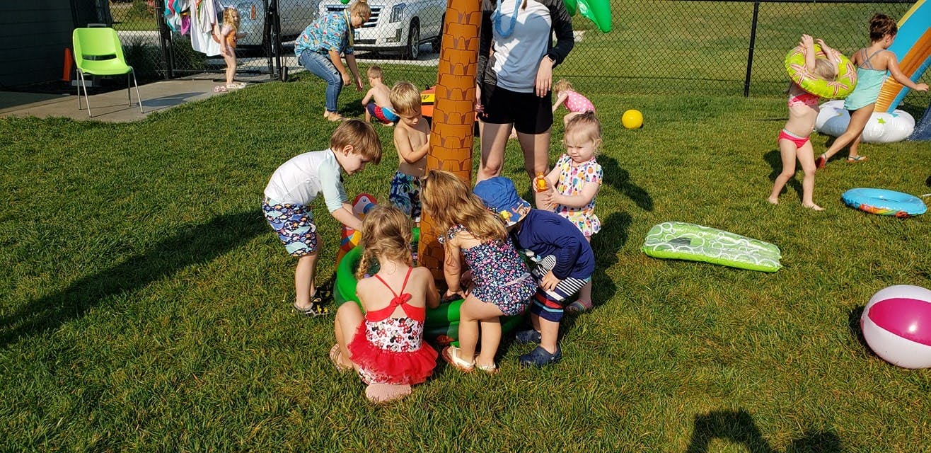 Children playing around a palm tree sprinkler