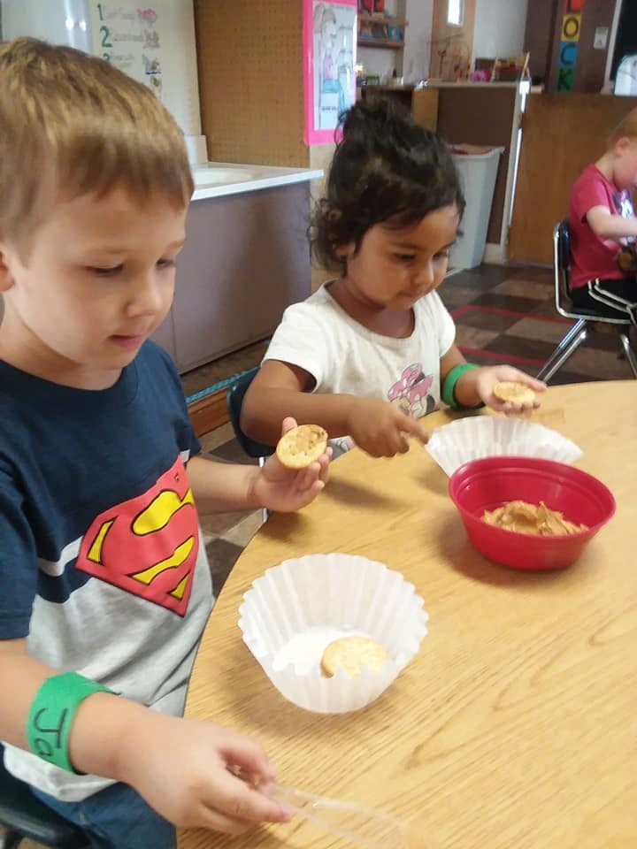 Two children making snacks at a table