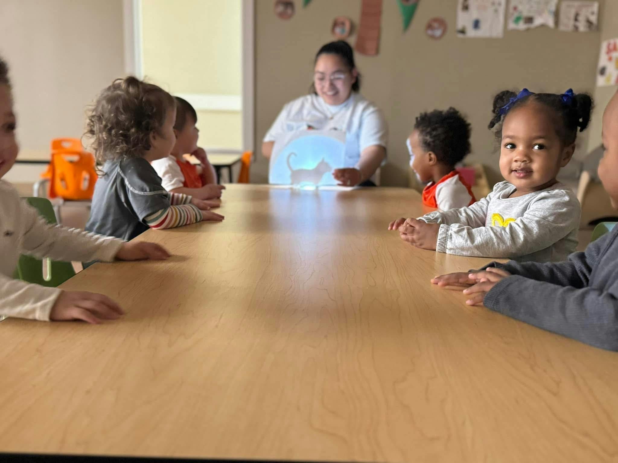Adult and children sitting at a table with a glowing elephant toy