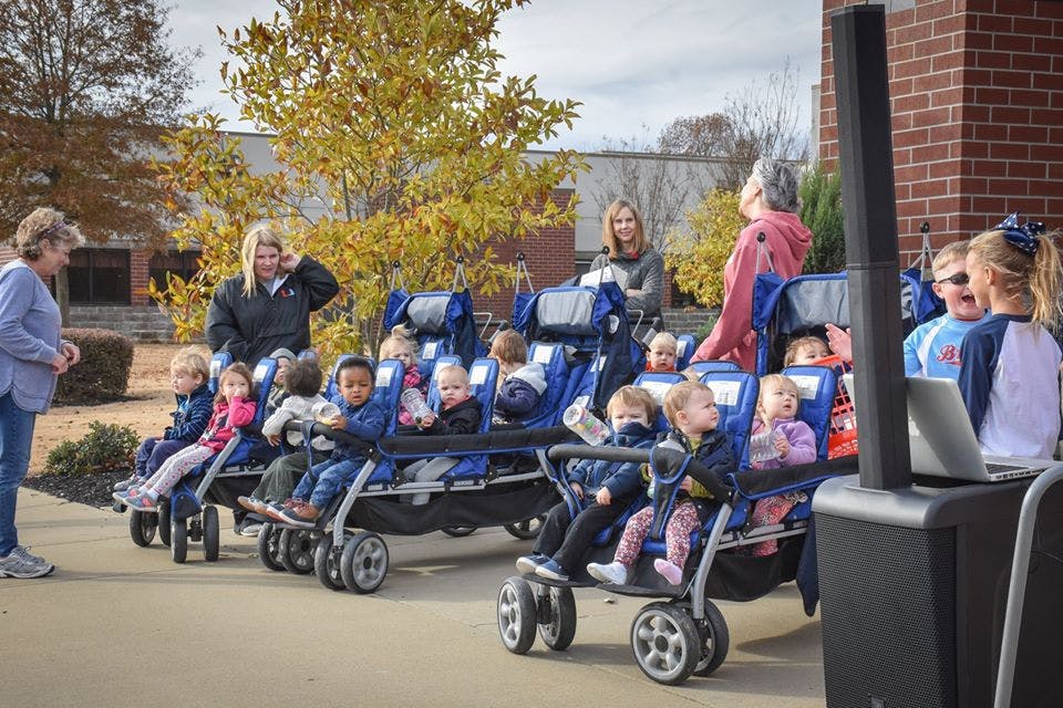 Adults with multiple children in multi-seat strollers outdoors