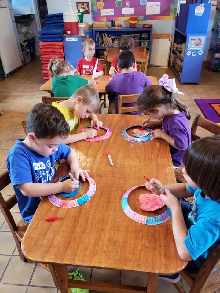 Children making crafts at a table in a classroom