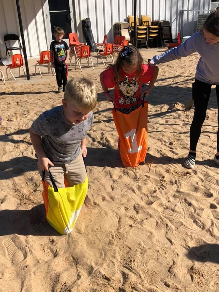 Children playing in sand with sack race bags