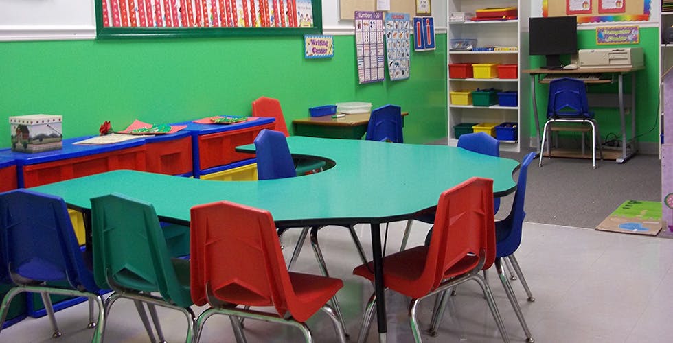 Classroom with green walls, colorful tables and chairs