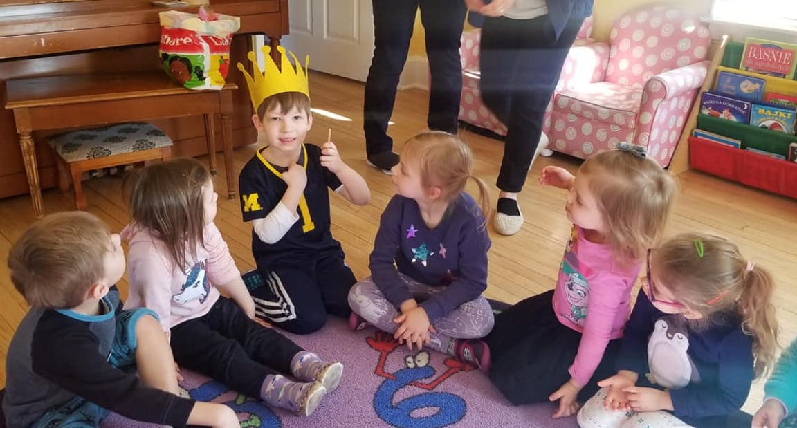 Child wearing a crown sitting on the floor with other children