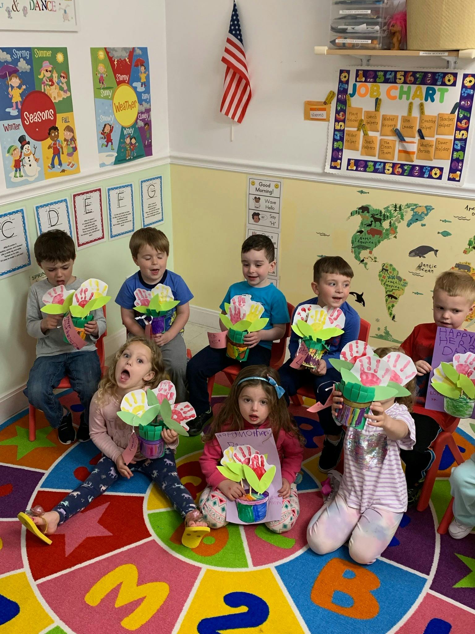 Children holding paper flower crafts in a classroom