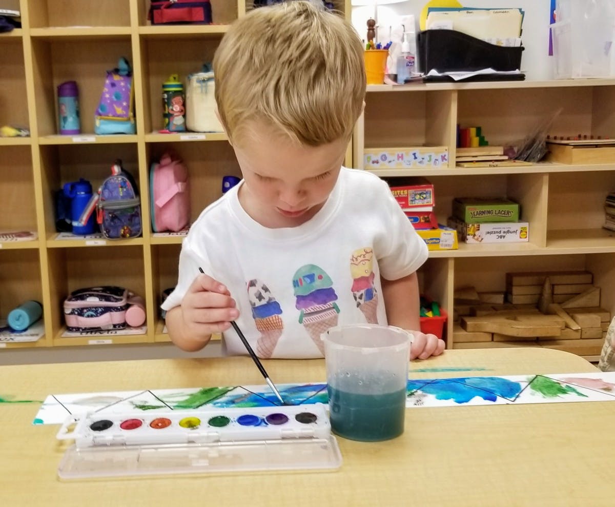 Child painting with watercolors at a table