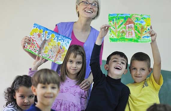 Adult and children holding up colorful drawings