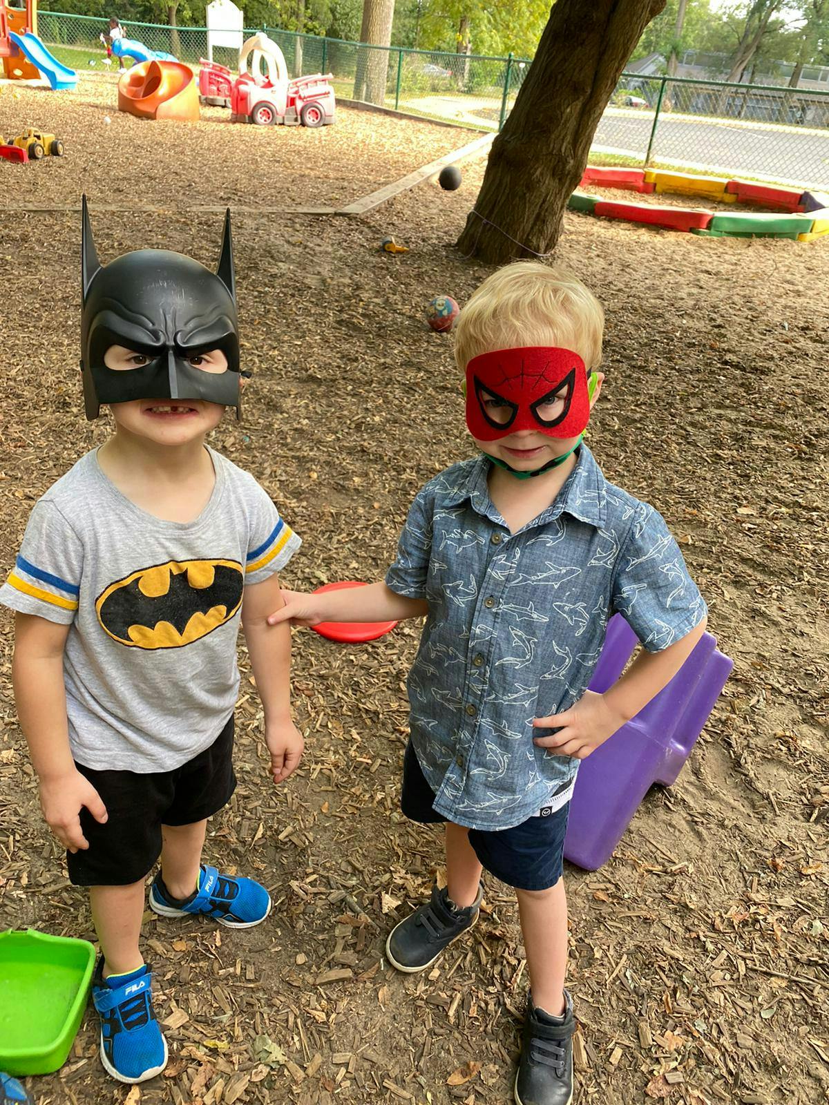 Two children in superhero masks standing outdoors
