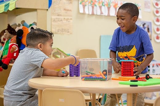 Two children playing with building blocks at a table