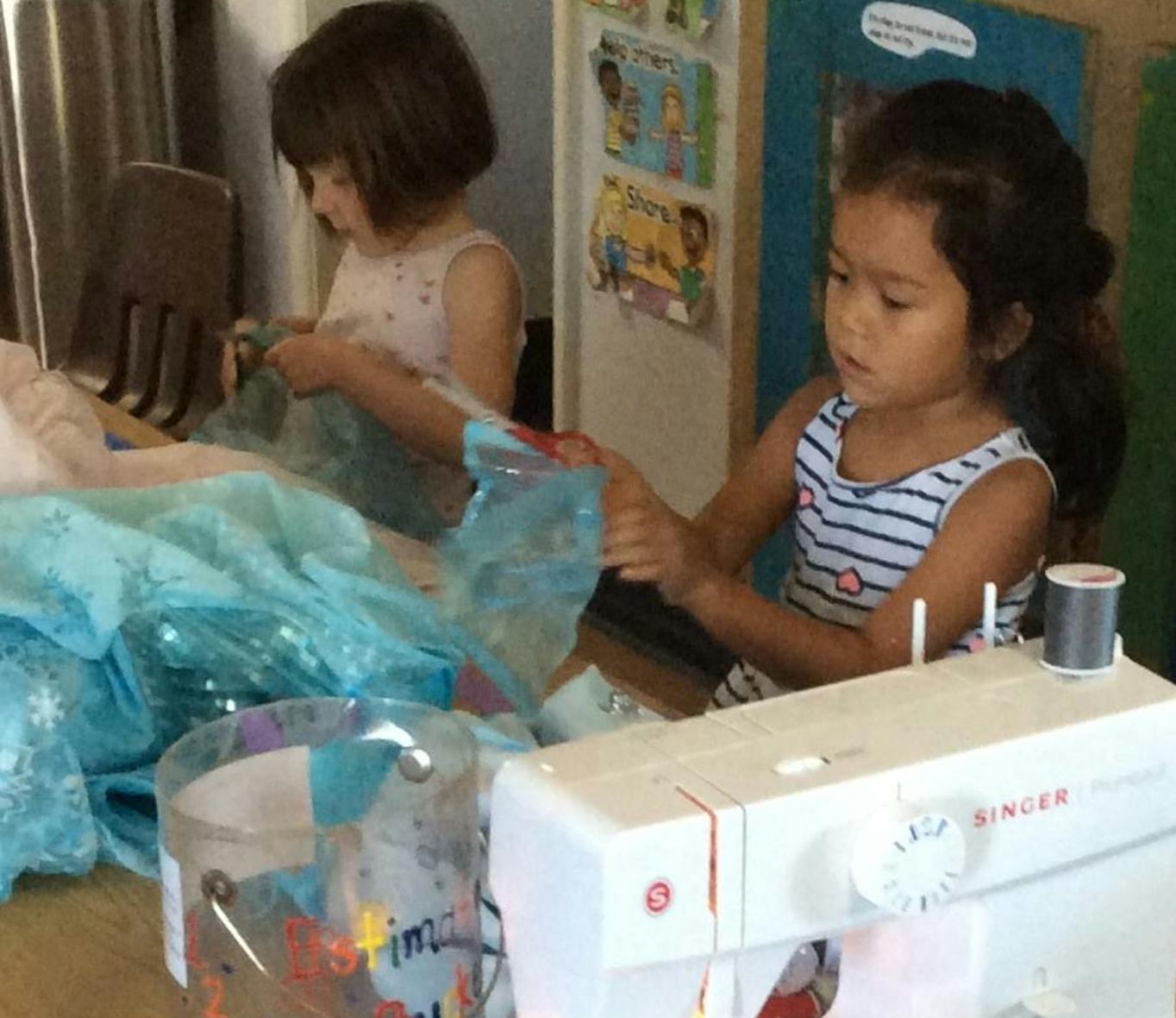 Two children working with fabric and a sewing machine