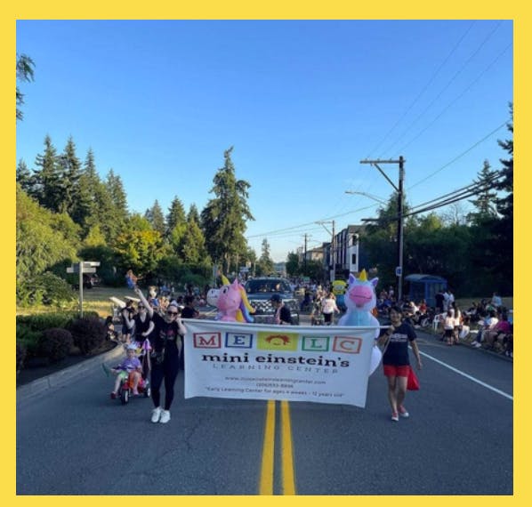 People holding a banner for Mini Einstein's Learning Center in a parade