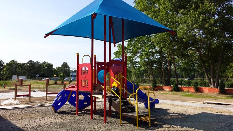 Playground structure with blue canopy, red and yellow slides, and stairs