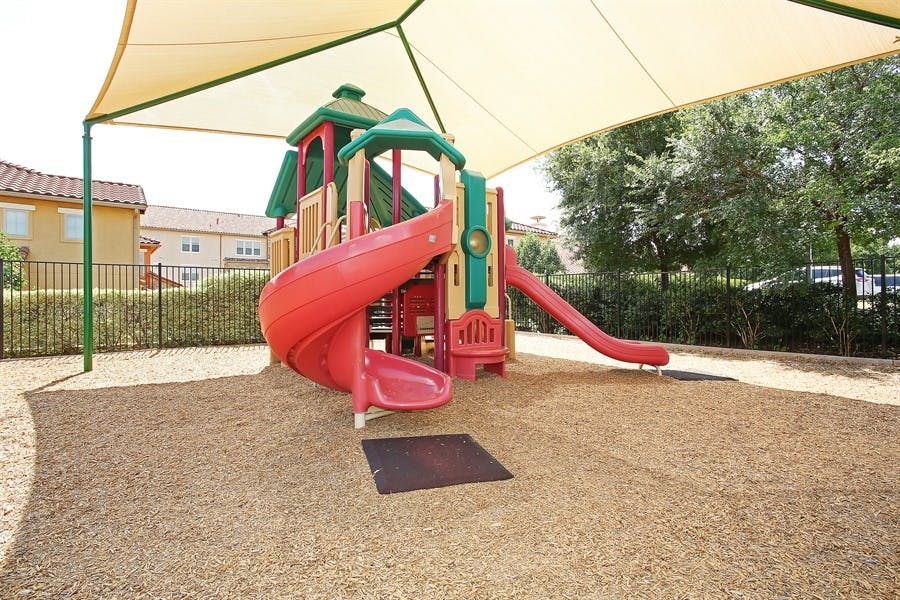 Playground with red and green slides under a shade canopy