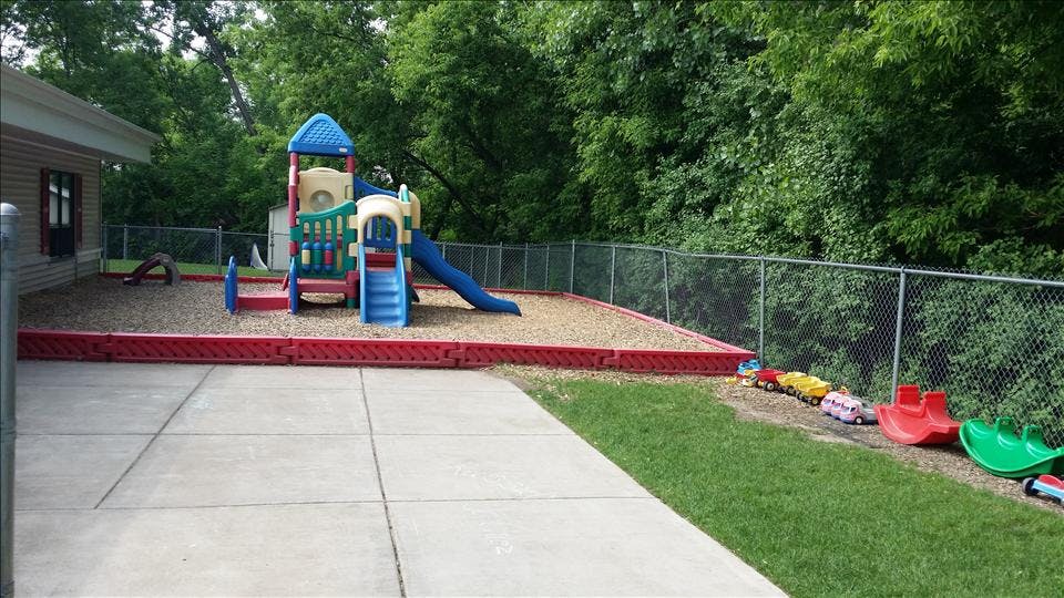 A colorful playground with a slide and climbing structure on wood chips