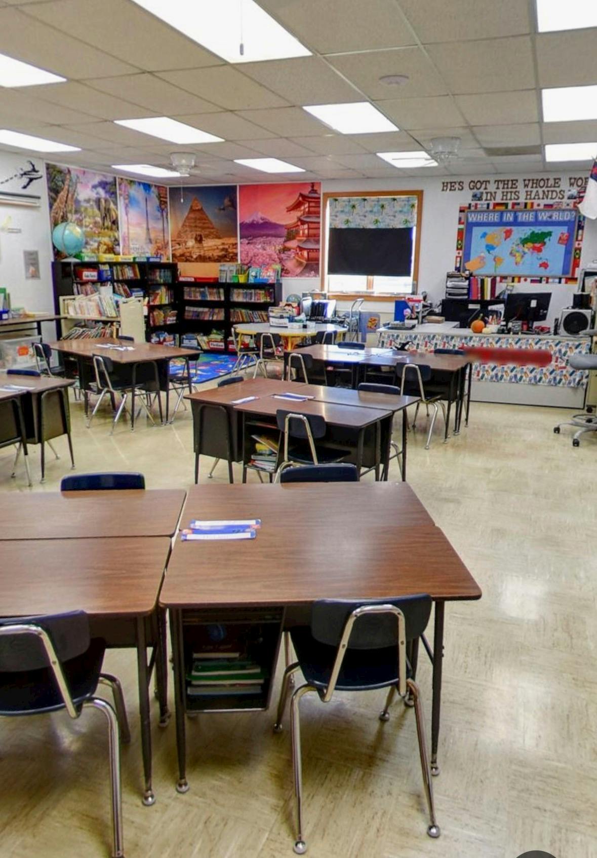 Empty classroom with student desks and chairs facing a teacher station