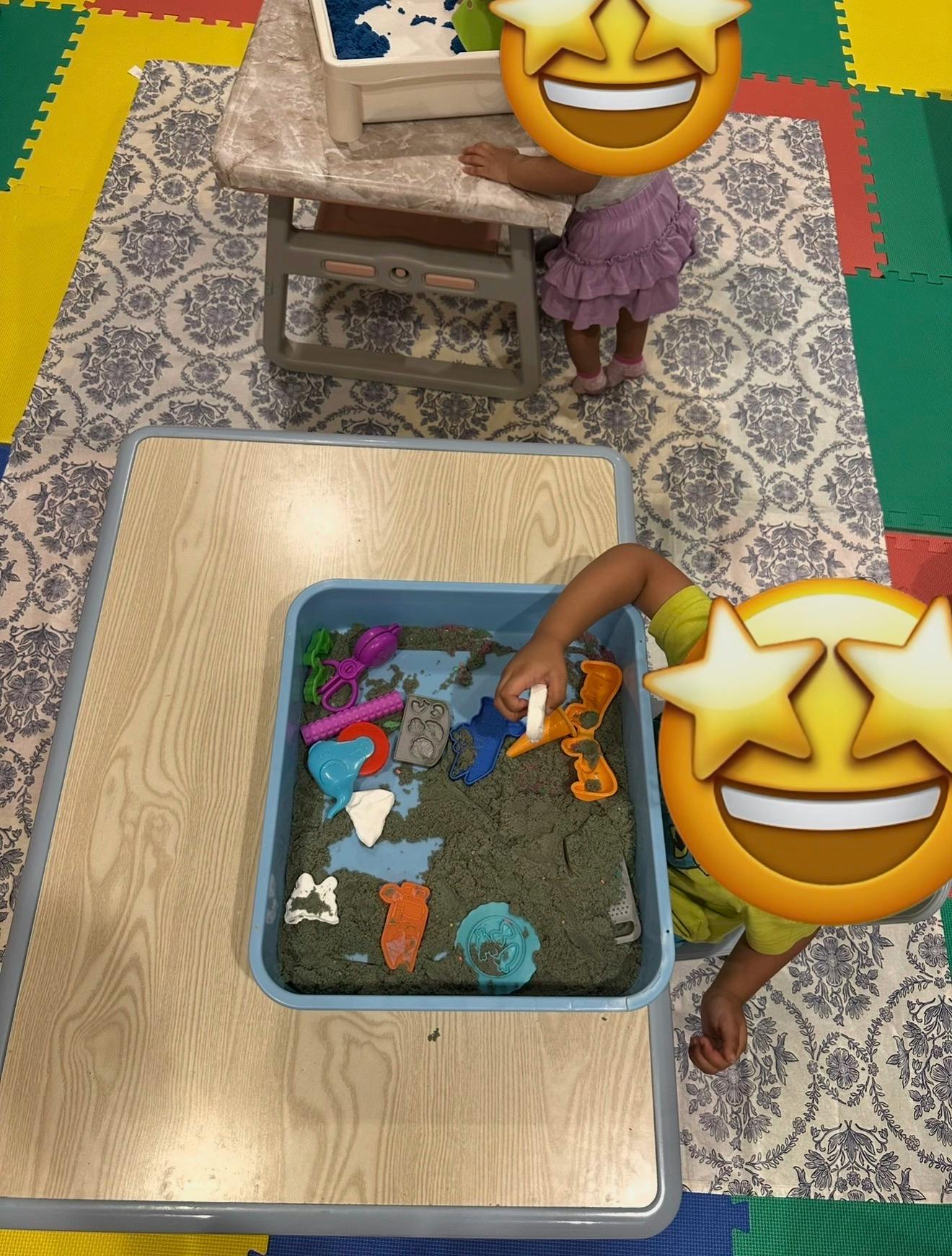 Two children playing with sand and molds at small tables
