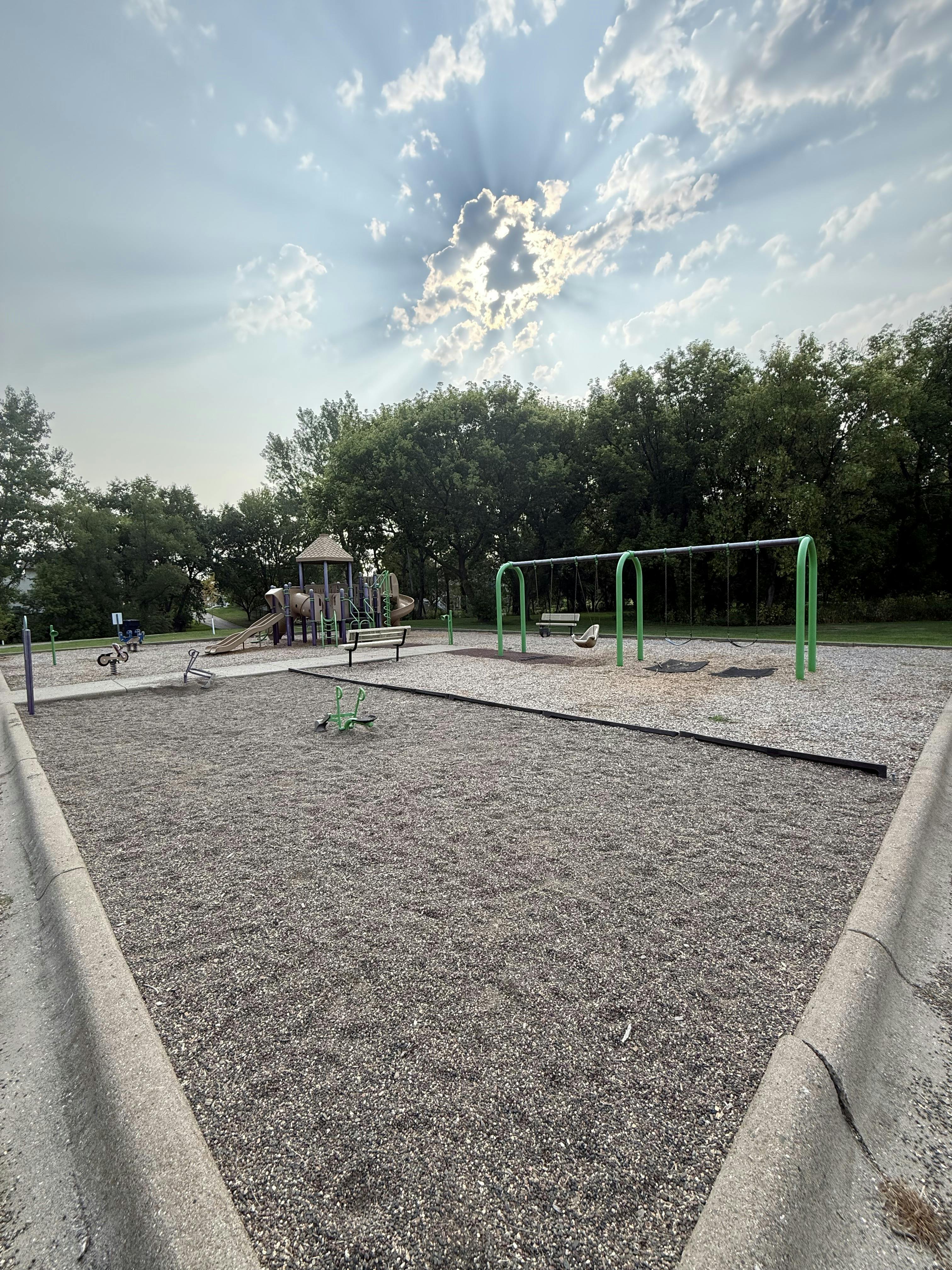 Empty outdoor playground with swings and climbing equipment