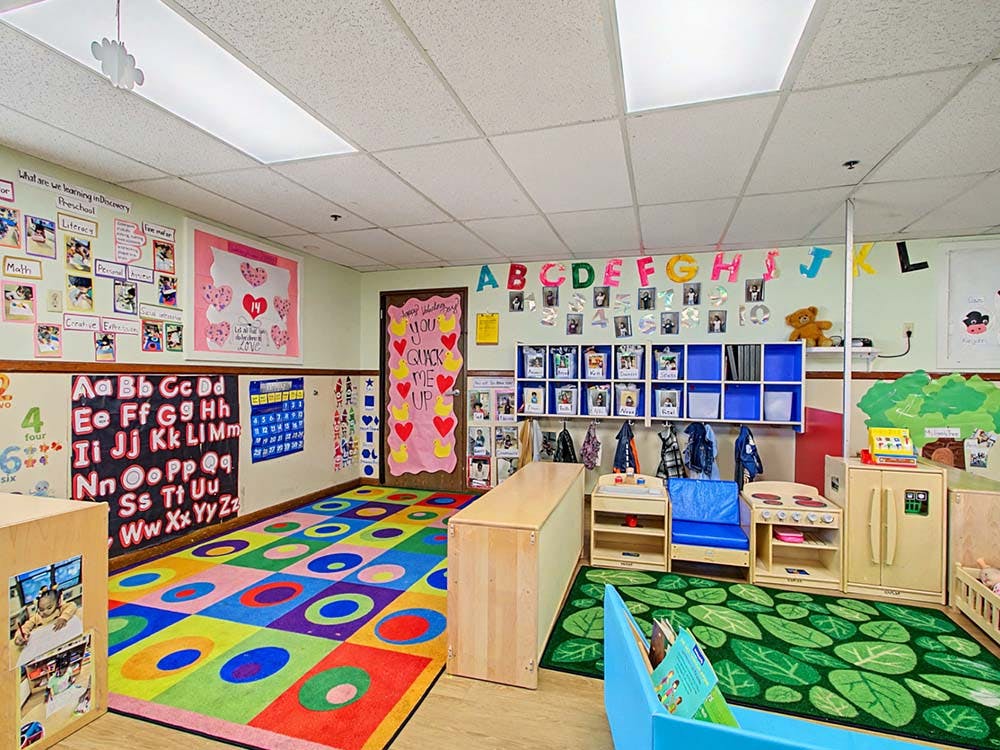 Colorful preschool classroom with various learning stations and wall decorations