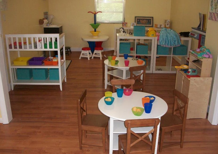 Playroom with small tables and chairs, shelves with toys
