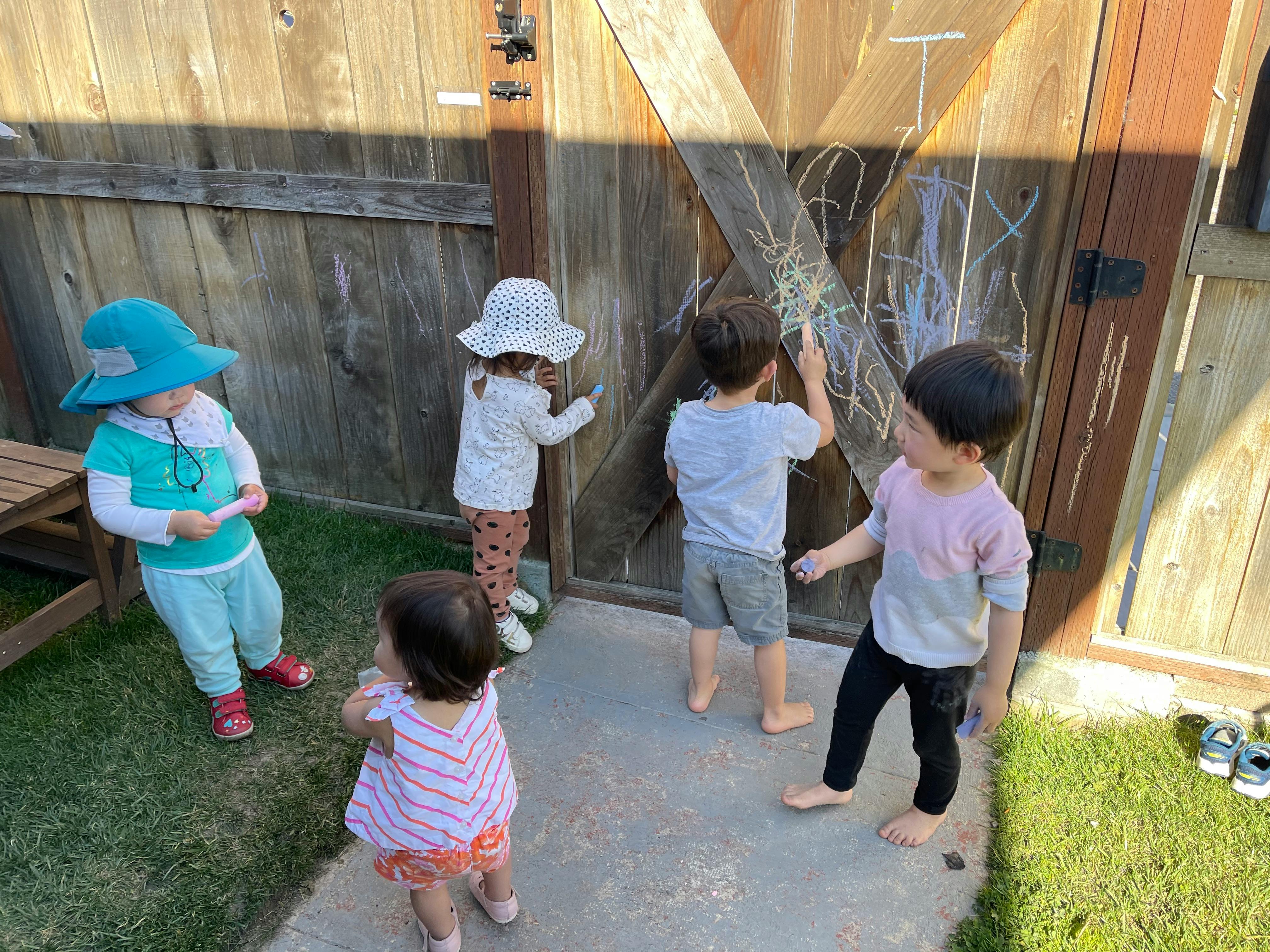 Children drawing on a wooden fence