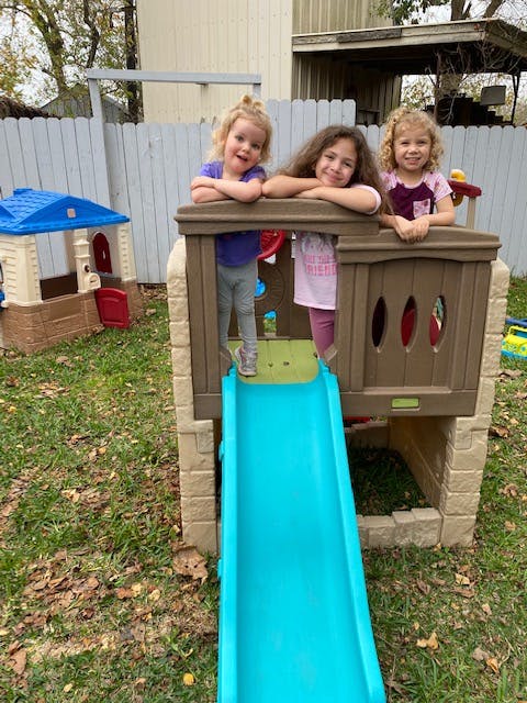 Three children on a playground structure with a slide
