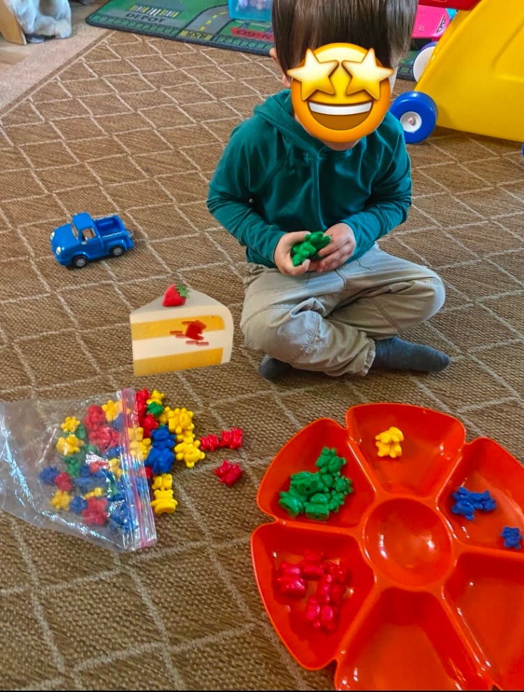 Child playing with colorful bear counters and a sorting tray