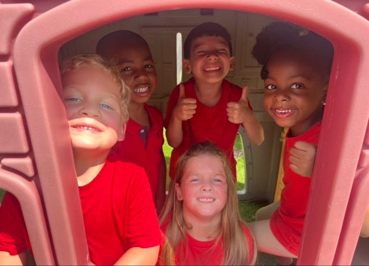 Five children in red shirts playing in a small structure