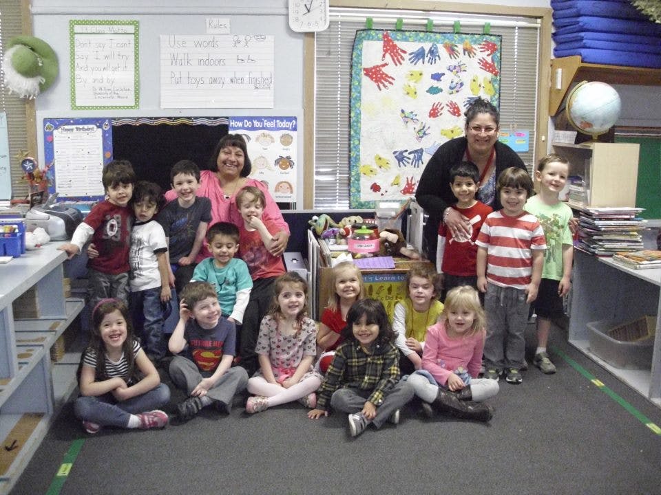 Two adults with a group of children in a classroom