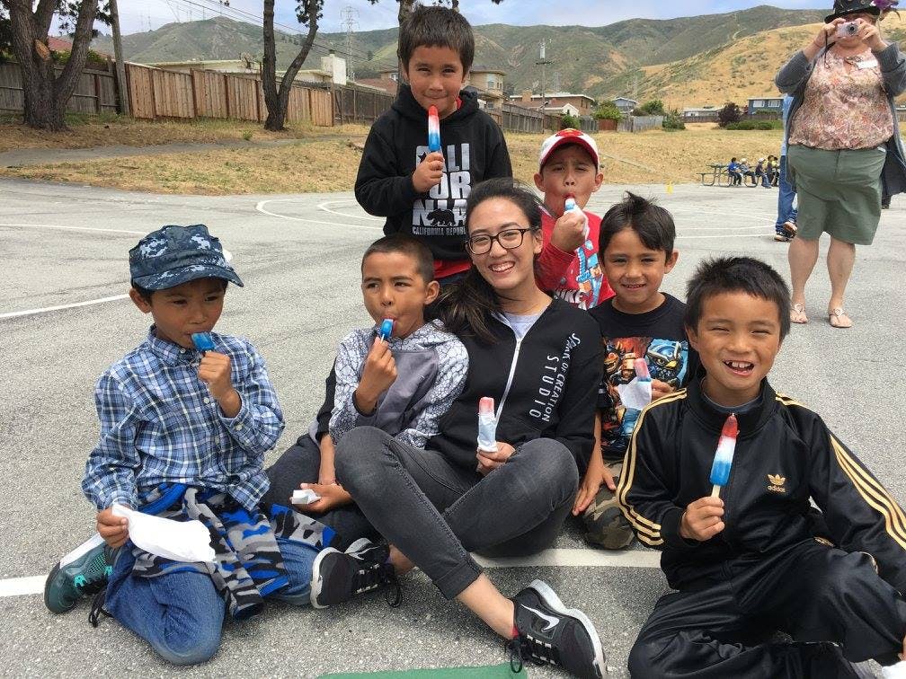 Person and multiple children eating popsicles outdoors
