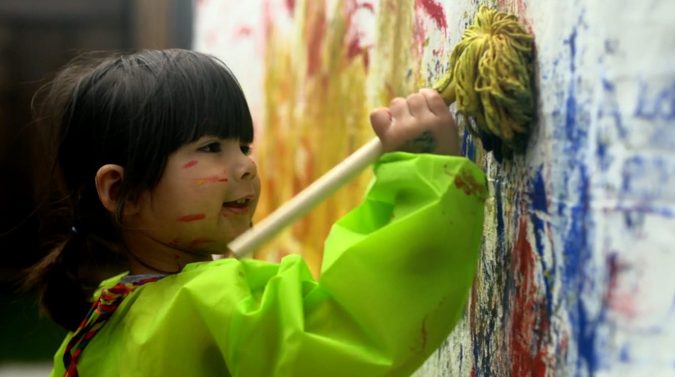 Child painting a wall with a mop