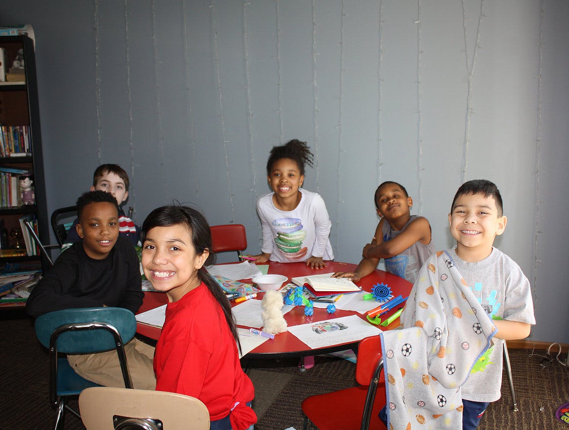 Group of children sitting around a table with art supplies