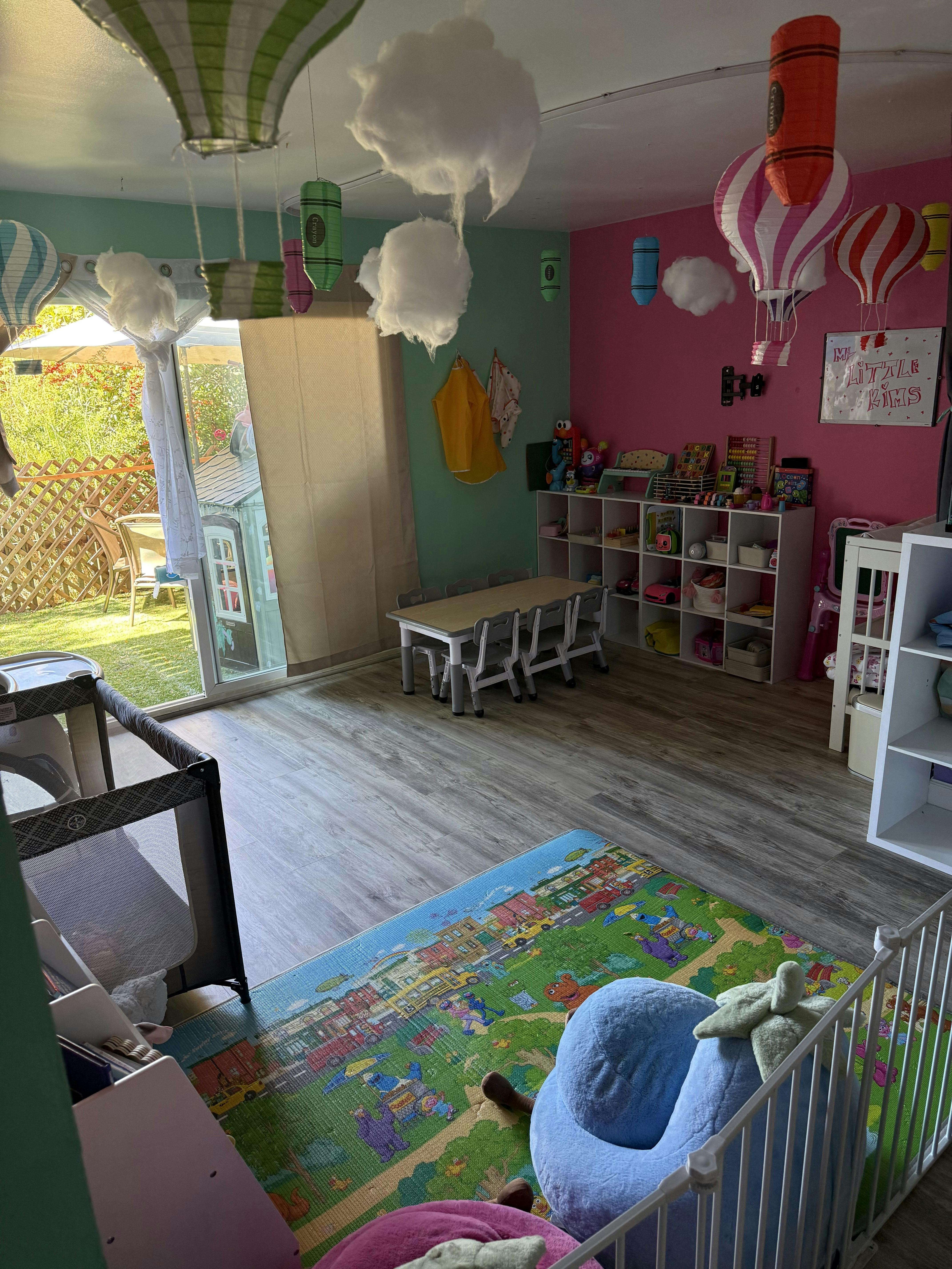 Playroom with small table, shelves of toys, and themed ceiling decorations