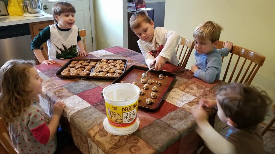 Children at a table with trays of cookies