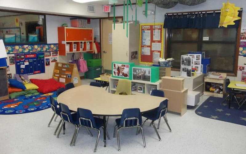 An empty classroom with a crescent-shaped table and small chairs