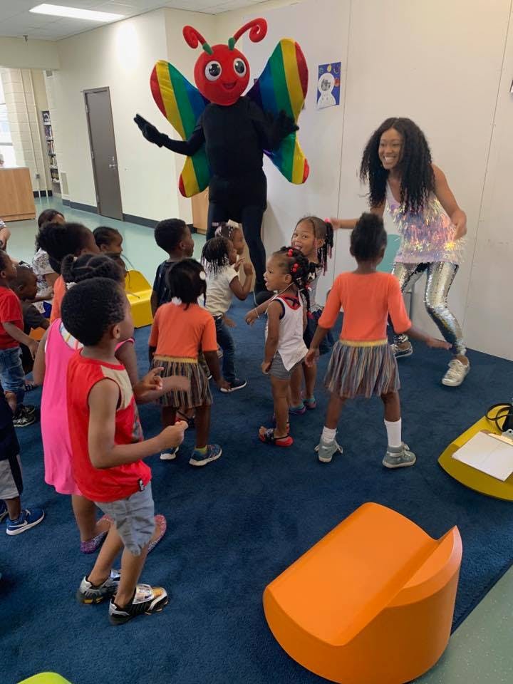 Person in butterfly costume and adult with children in a classroom