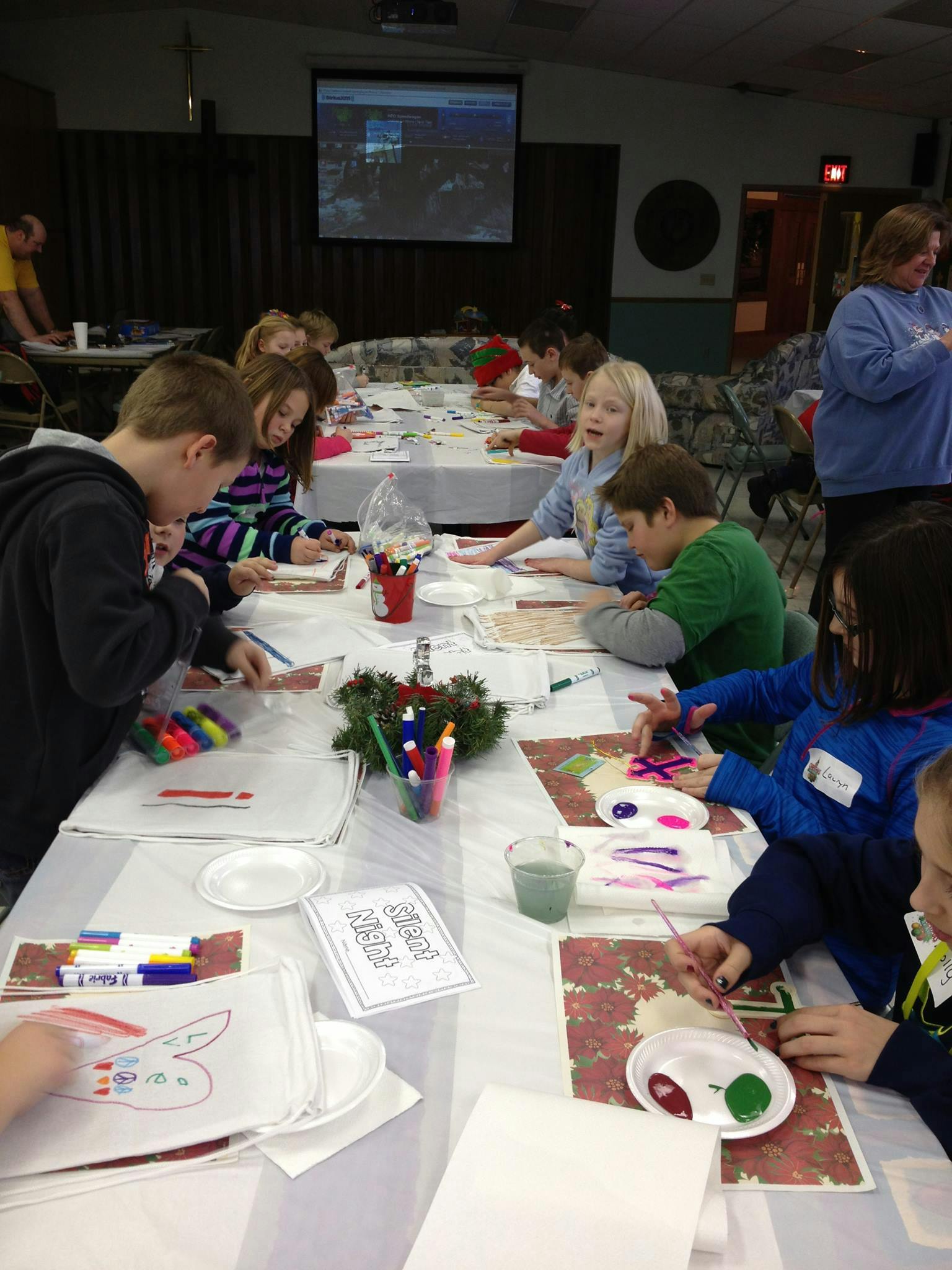 Children sitting at tables doing crafts with markers and paint