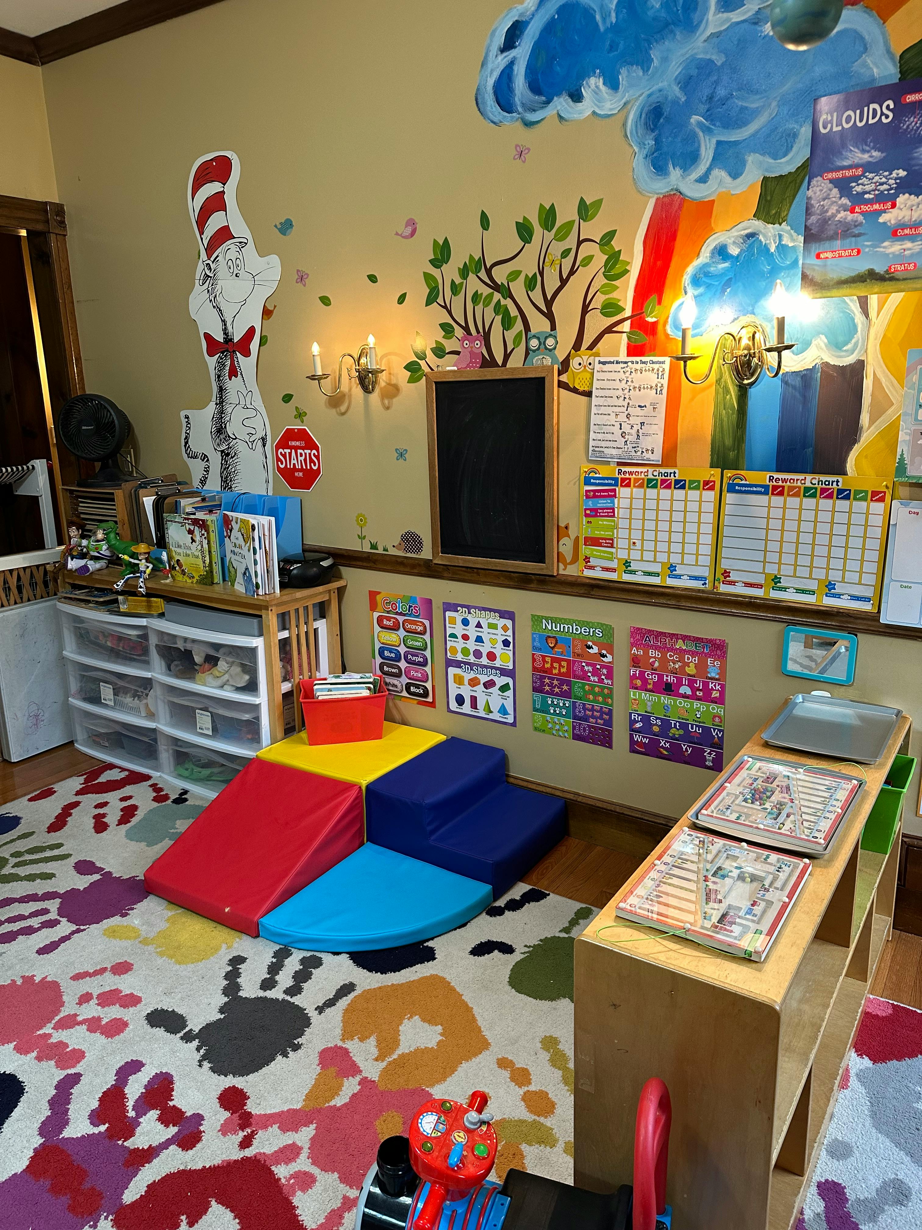 Playroom with colorful soft play equipment on a rug with handprints
