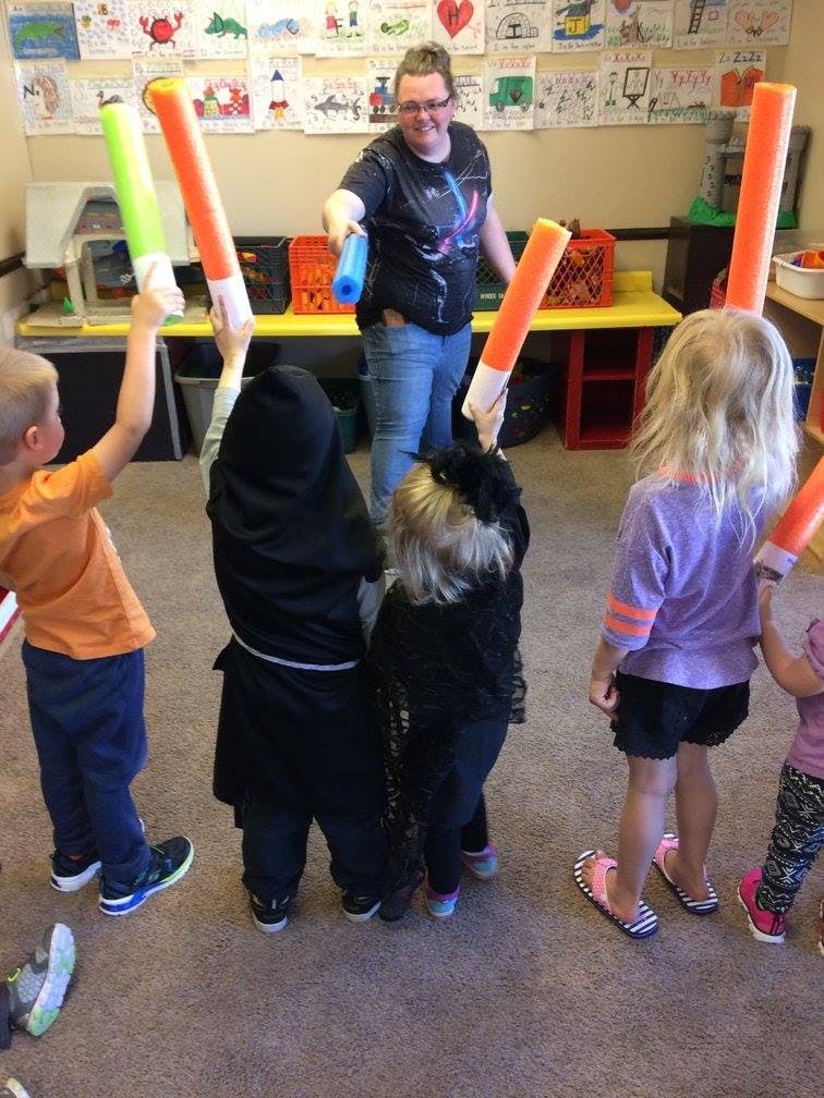Adult and children playing with foam pool noodles in a room